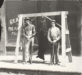 1915-rml-0233b-two-men-in-front-of-meat-market-with-bear.png