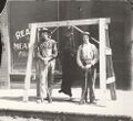 1915-rml-0233b-two-men-in-front-of-meat-market-with-bear-1600.jpg